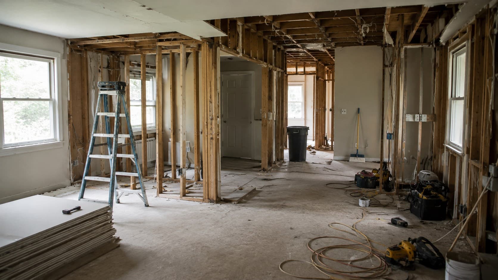 Interior renovation jobsite with exposed framing, ladder, and tools
