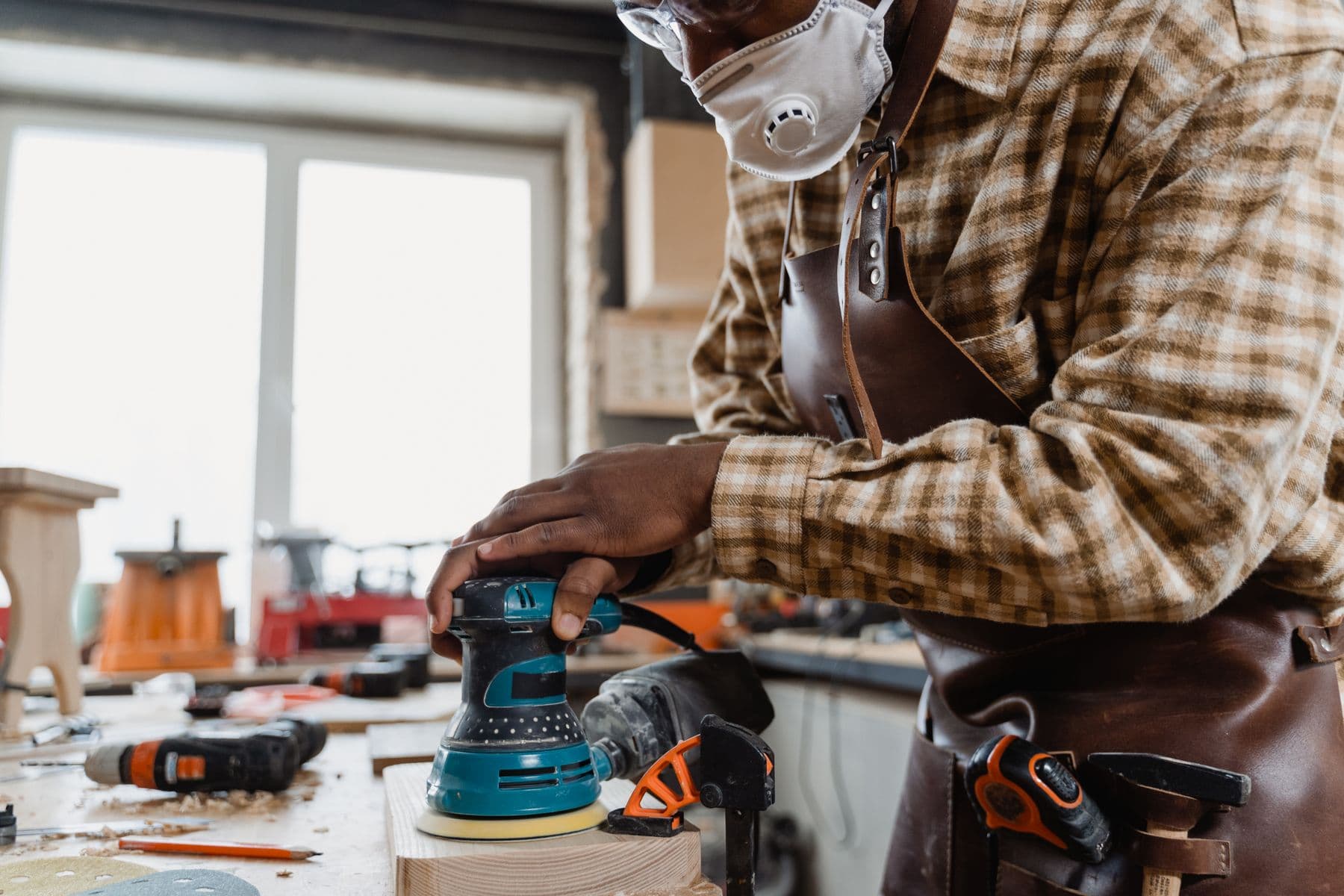 Skilled carpenter sanding a custom piece of wood in a working shop